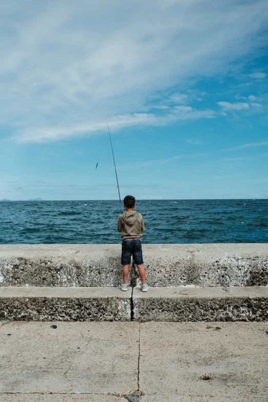 man standing on the beach fishing from a perch