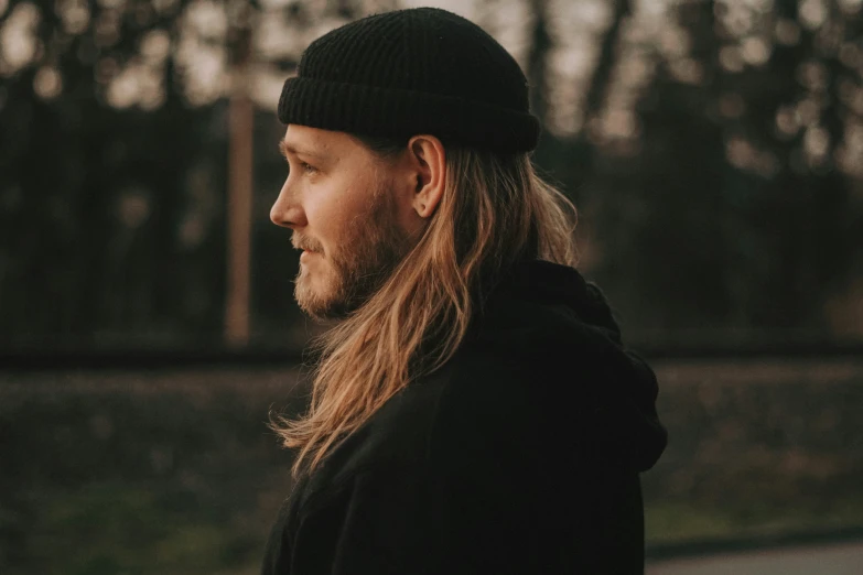 a man with long hair is standing outdoors