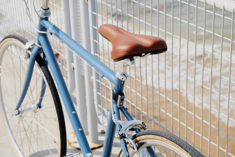 a blue bicycle locked to a white fence