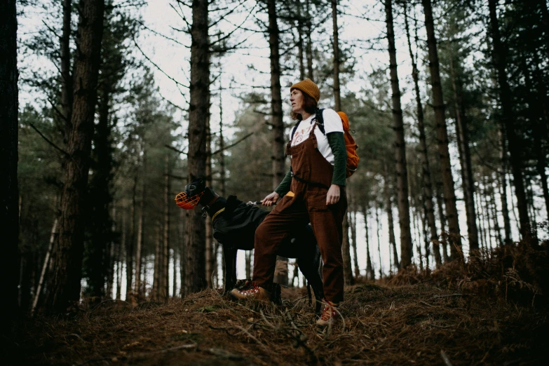 a man wearing an orange and white vest standing next to a dog