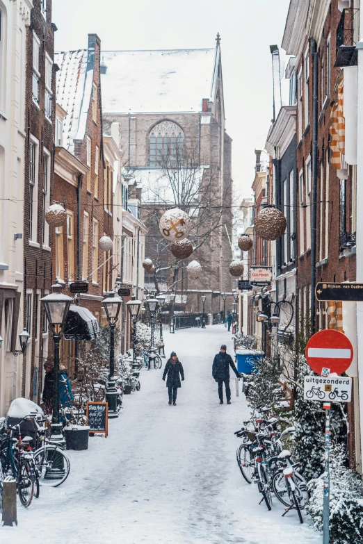 two people walking down a snowy street in a european town