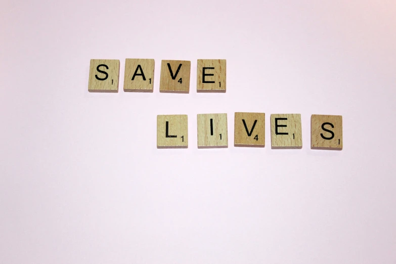 scrabbled letters spelling save lives on top of a wall