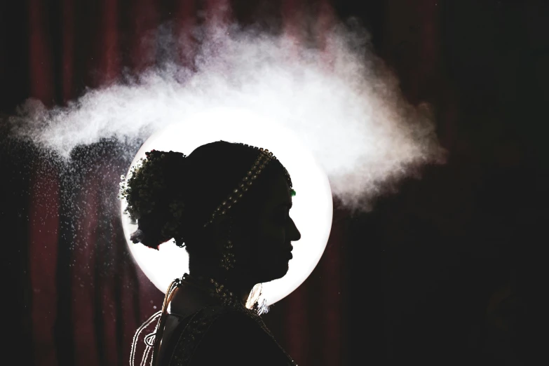 a female in a dark room with a white moon behind her