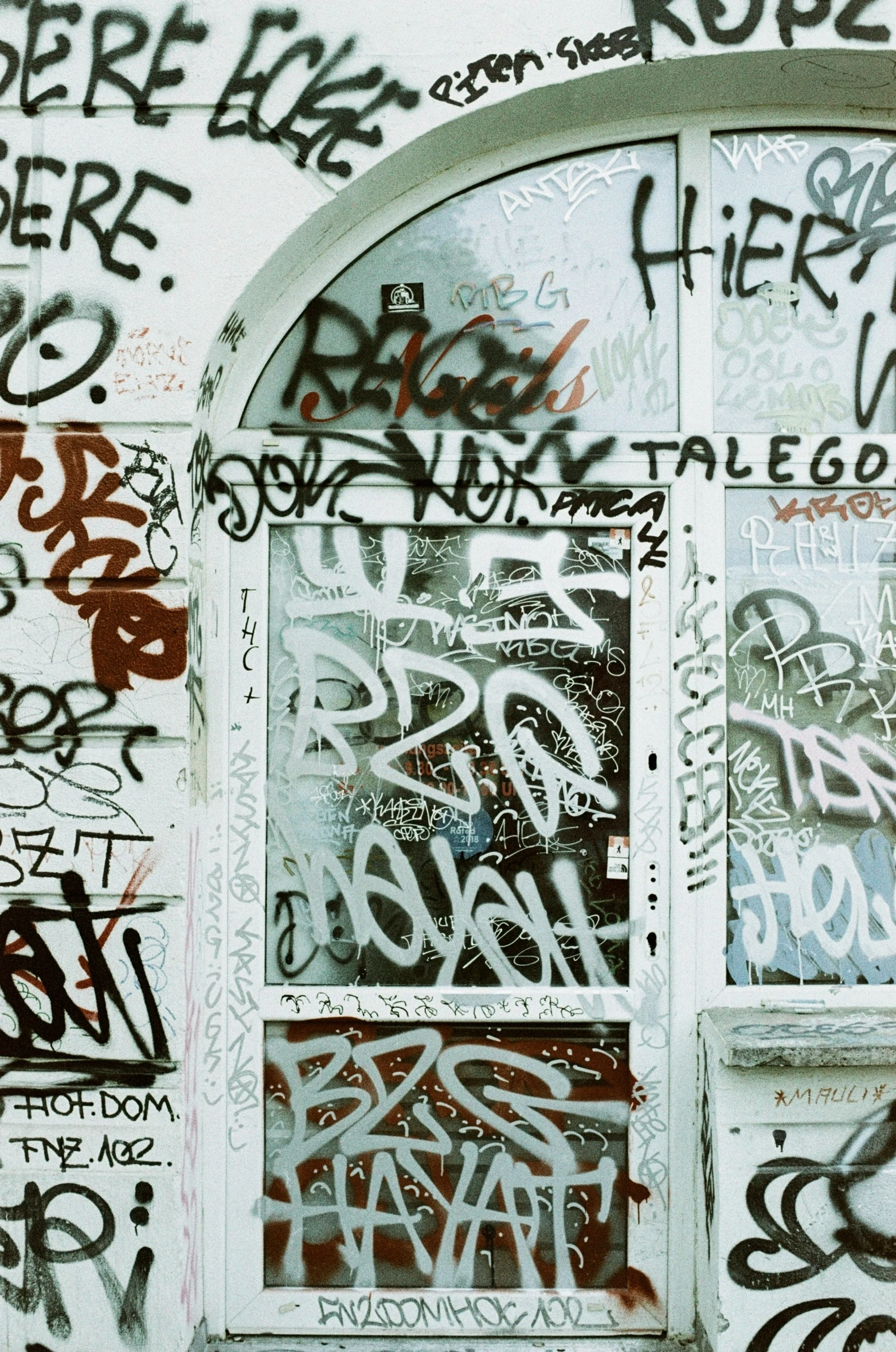 there is a window covered in graffiti next to a wall