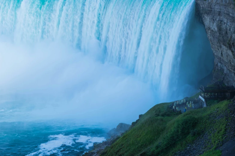 people at the base of niagara falls with a waterfall in the background