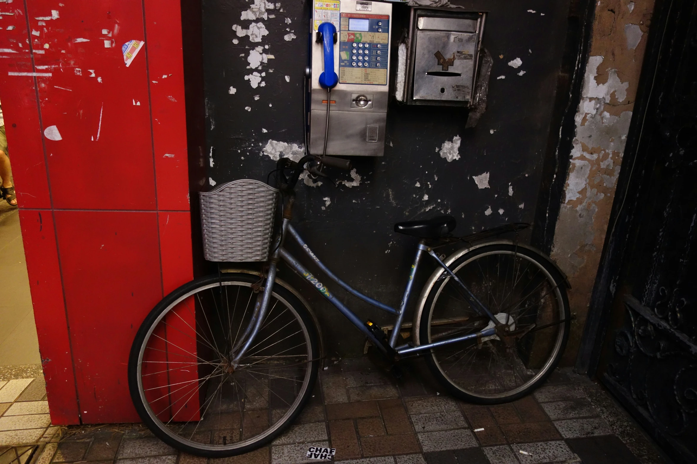 a black bike leaning against a telephone booth