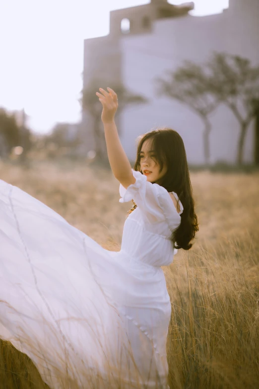 a girl in a white dress stands on a field in tall grass