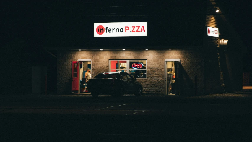 a car sitting in front of a pizza shop