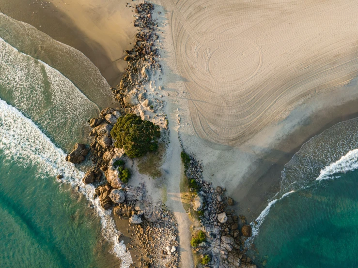 an aerial view of a beach with waves breaking around it