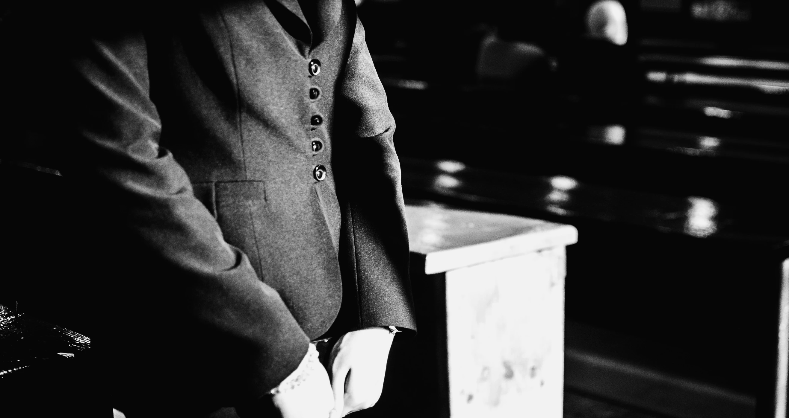 a man in a suit standing by a wooden table