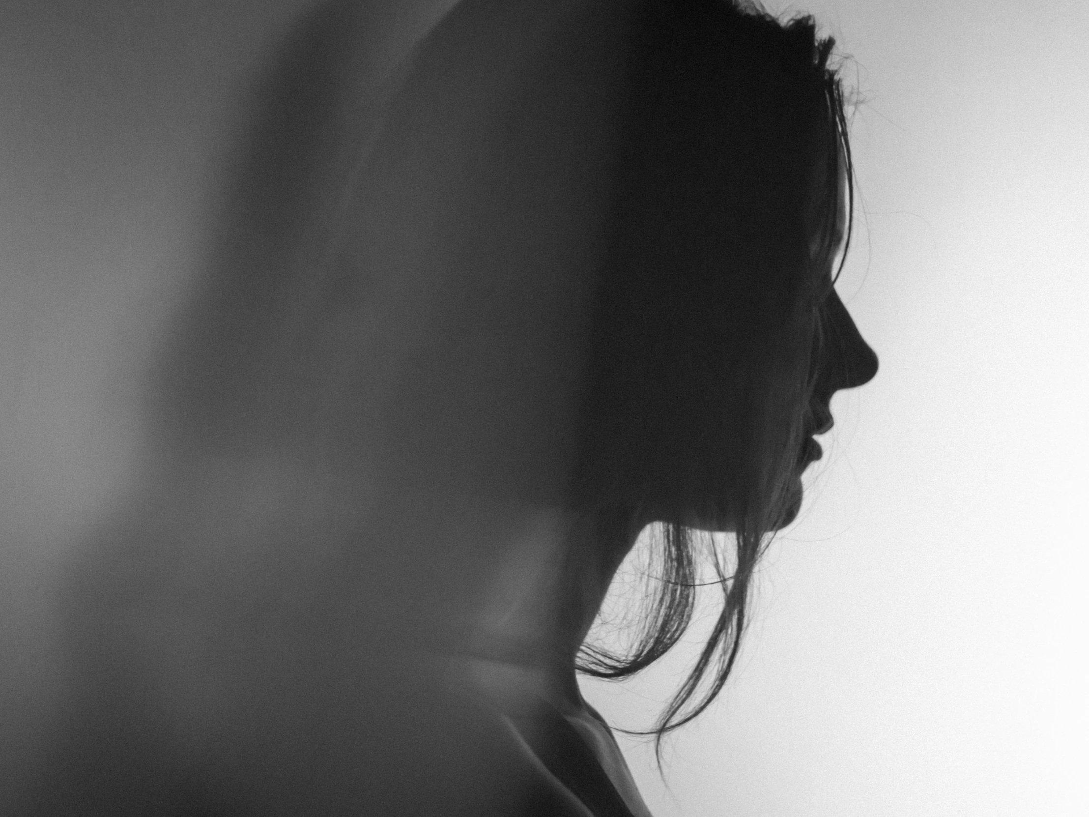 a woman is shown in silhouette next to a white wall