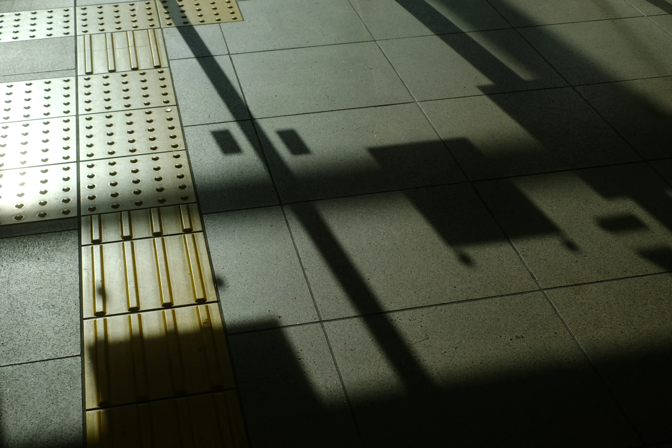 shadow of an umbrella next to an empty bench