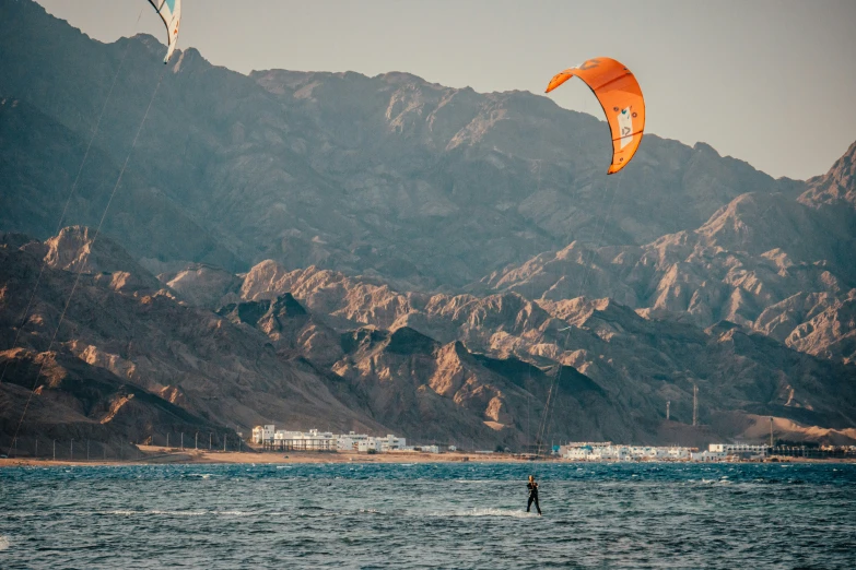 people kite board in the ocean near some mountains