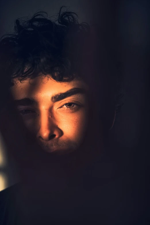 a young man standing in front of a light, making his face with the sun on the background