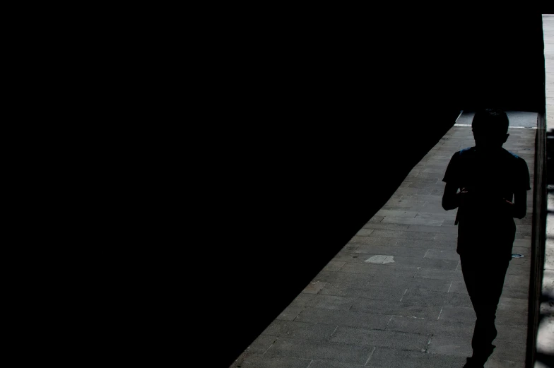 the silhouette of a man walking in a dark tunnel