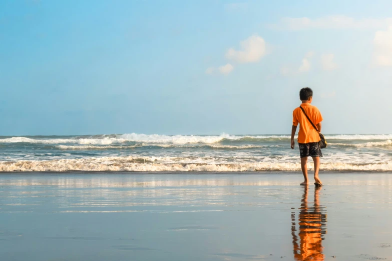 a man walking on the beach looking out at the ocean