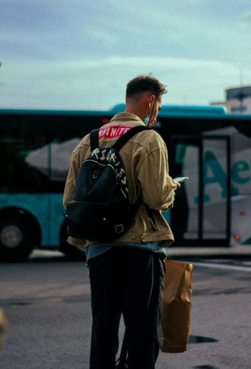 a man wearing a backpack standing in front of a bus