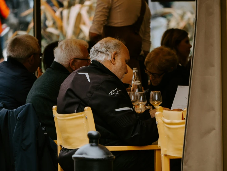 an older gentleman is sitting outside at a cafe eating