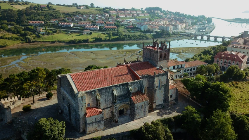 an old church has a red roof in the middle of a village