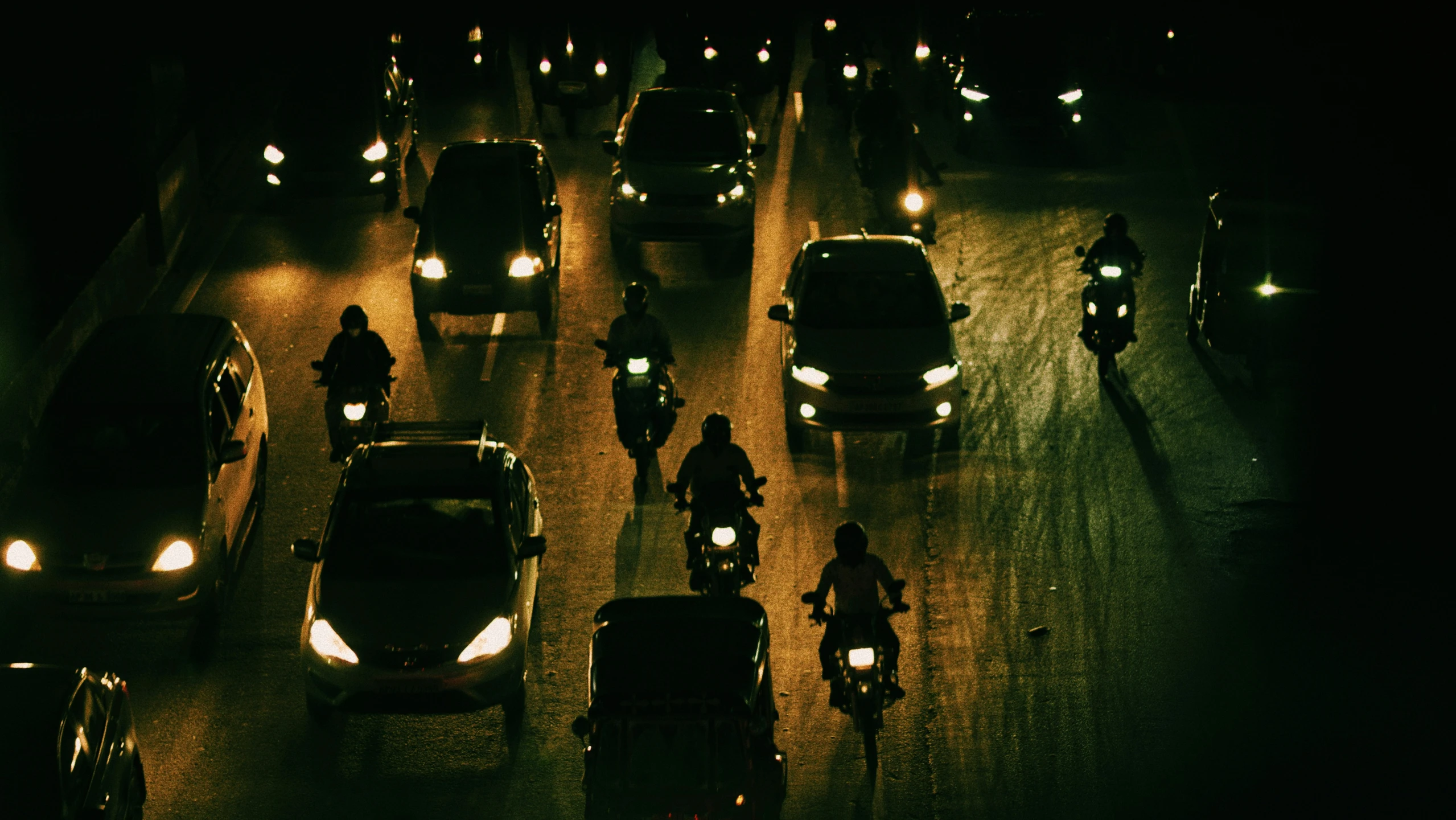 cars and people riding their bikes down a crowded city street at night