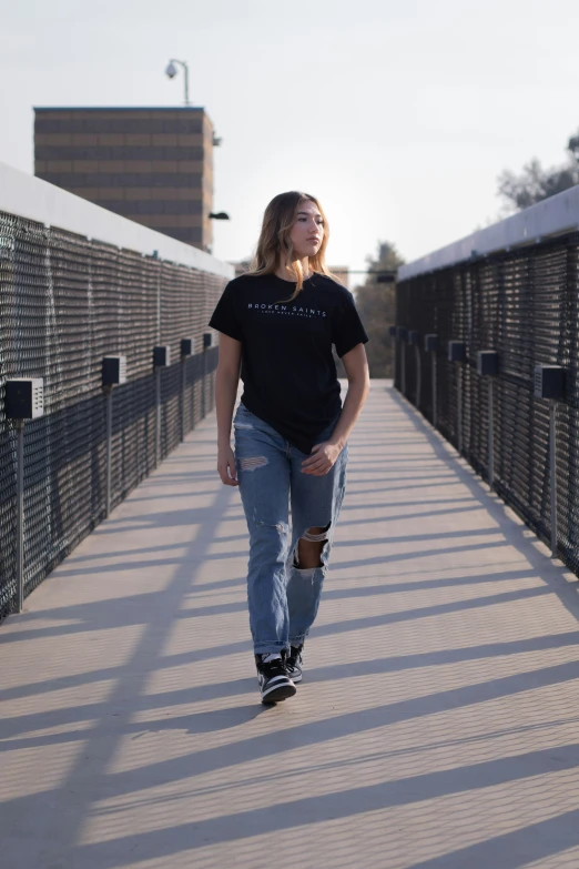 a beautiful young lady walking across a bridge