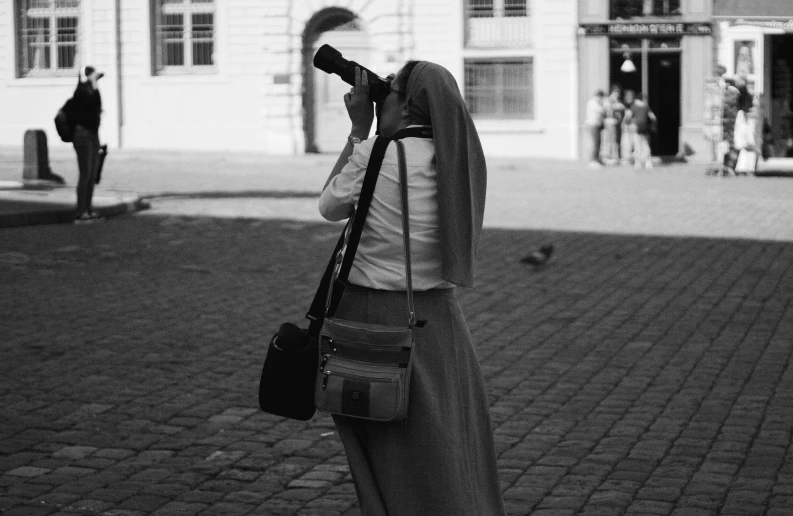 a woman taking a picture of people walking on the street with her cell phone