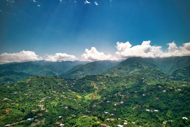 a valley covered in mountains under a cloudy blue sky