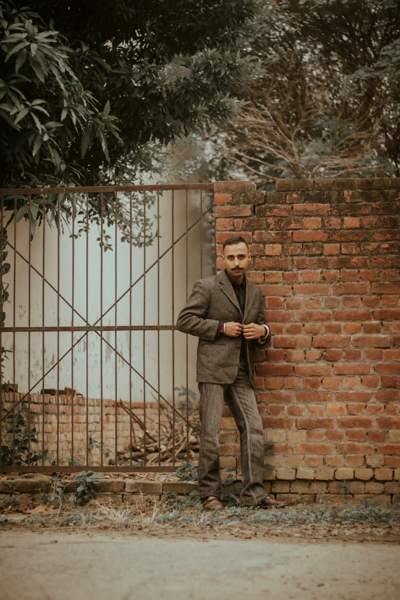 a person leans against a brick wall behind a fence