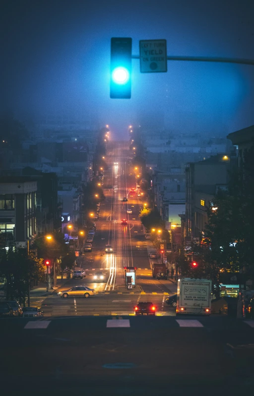 a green traffic light sitting above a city street at night