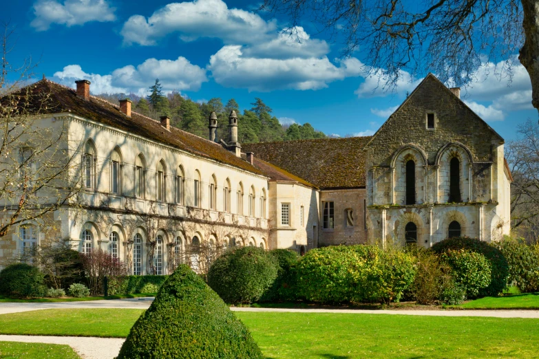 a stone building with a large lawn surrounded by hedges