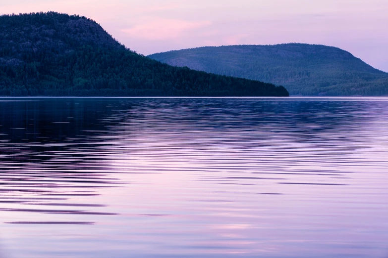 a body of water that has some hills in the background