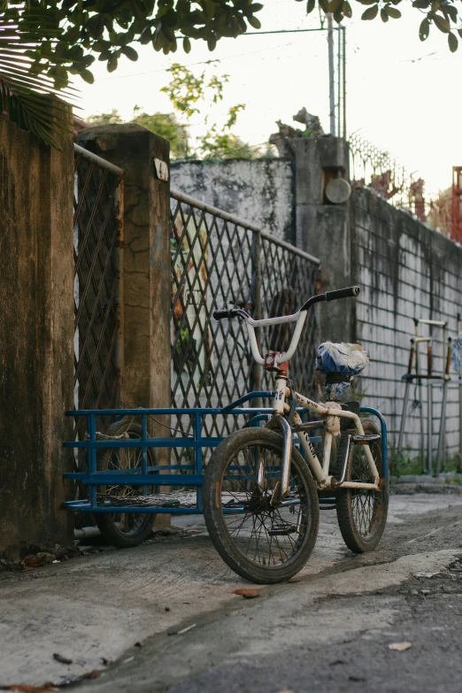 a bike is sitting on the street next to a blue cart