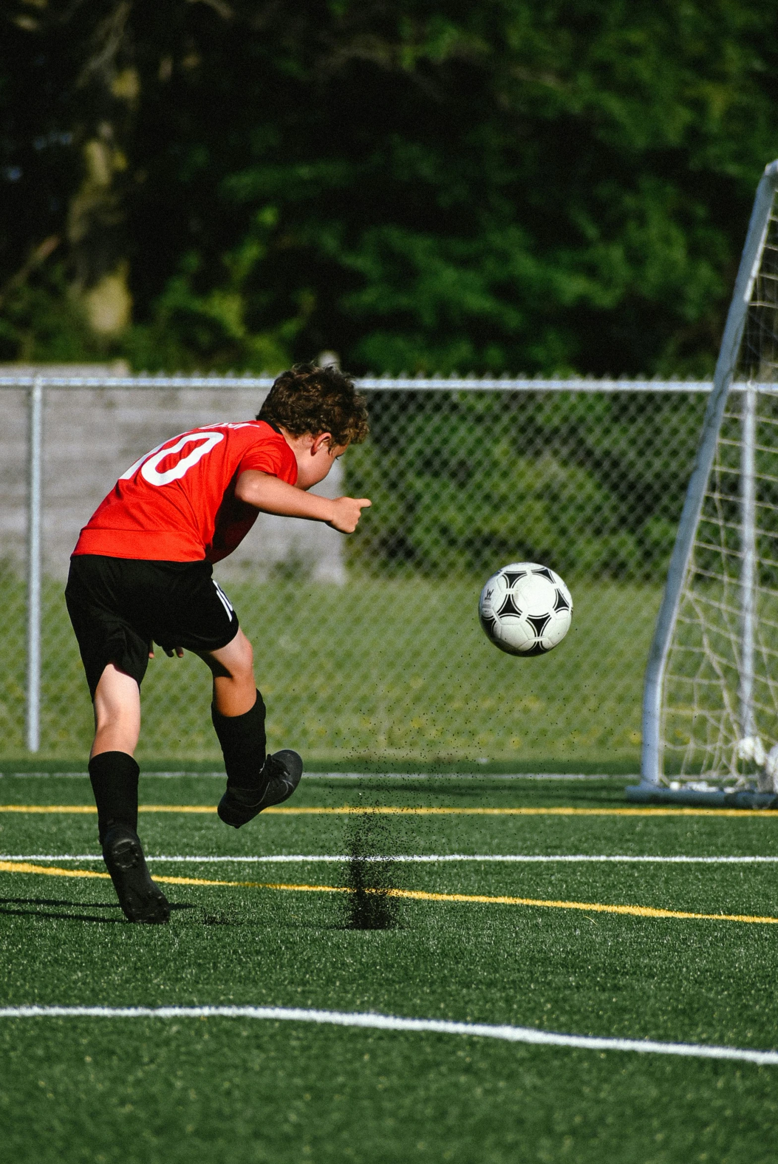 a soccer player wearing red kicks the ball