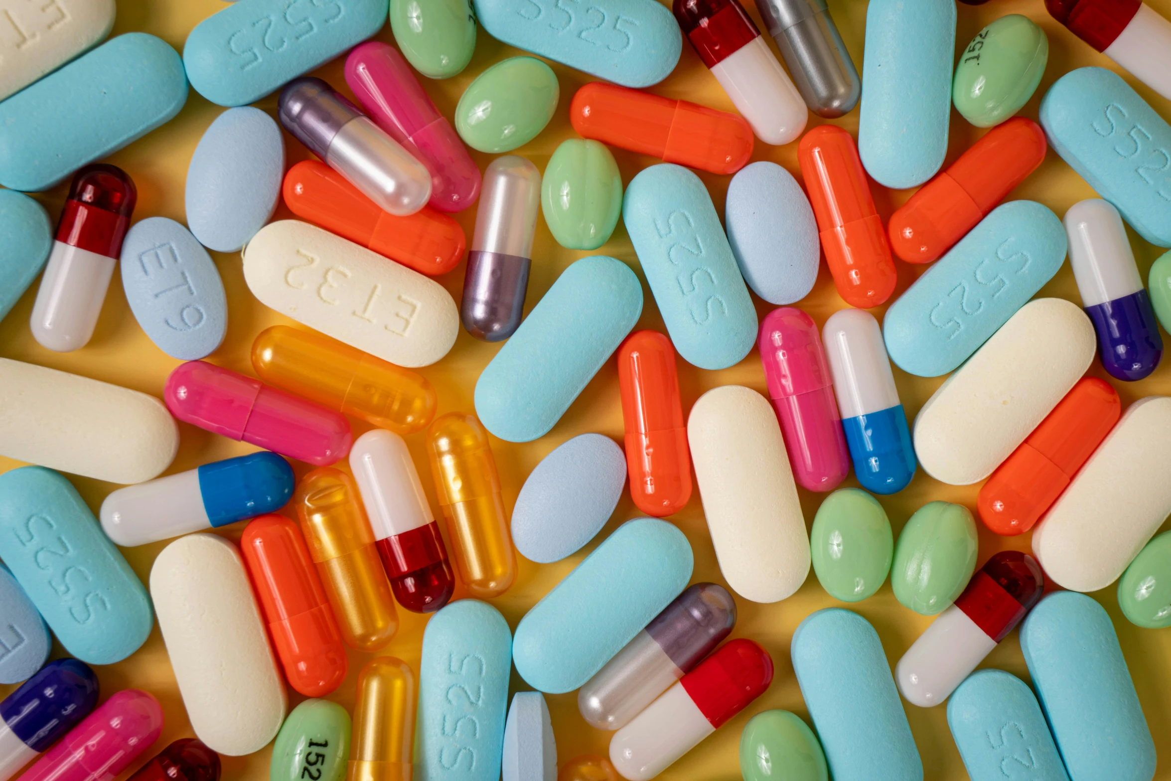 many colorful pills are on a white surface