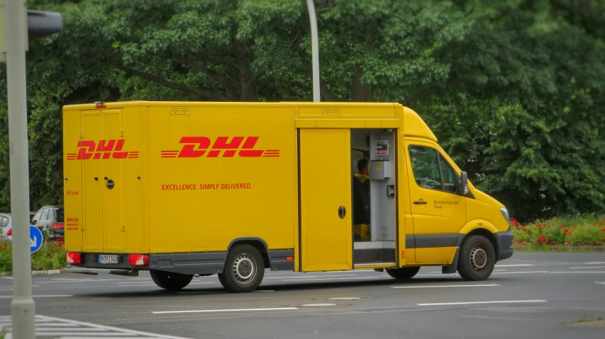 a large yellow moving van sitting in front of a park