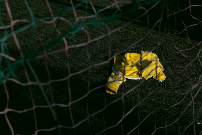 the yellow and white baseball glove is lying on the ground