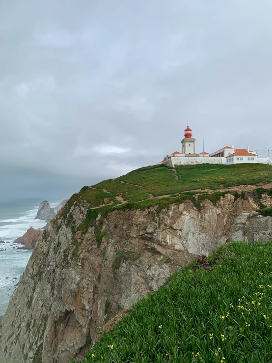 there are two white and red light houses on a rocky cliff