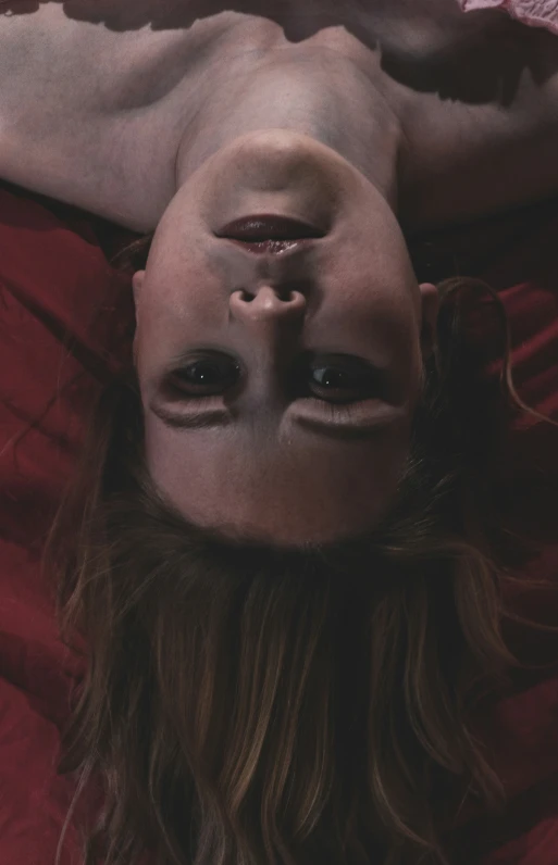 a woman in red lying on her side with a human face in her eyes