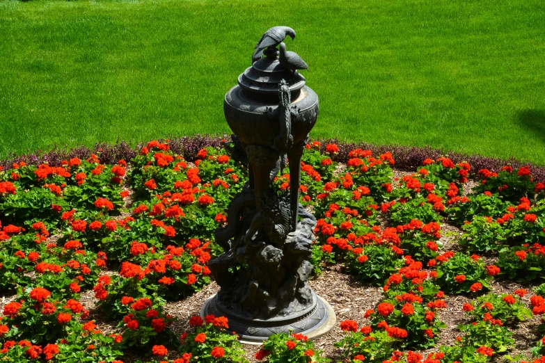 a statue in a garden area with flowers