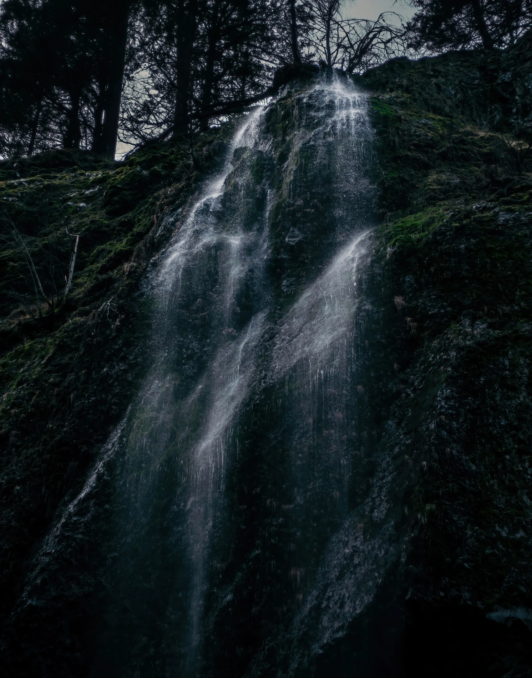 the side of a waterfall surrounded by trees