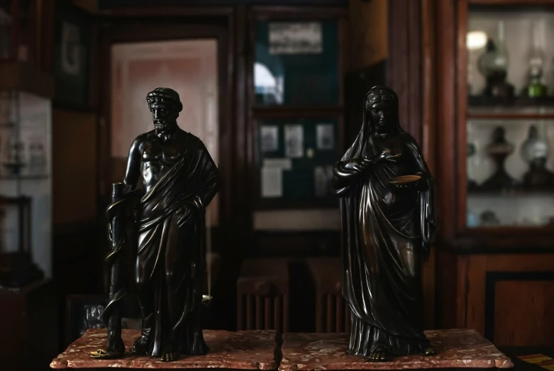 two sculptures standing on top of bookshelves in a room