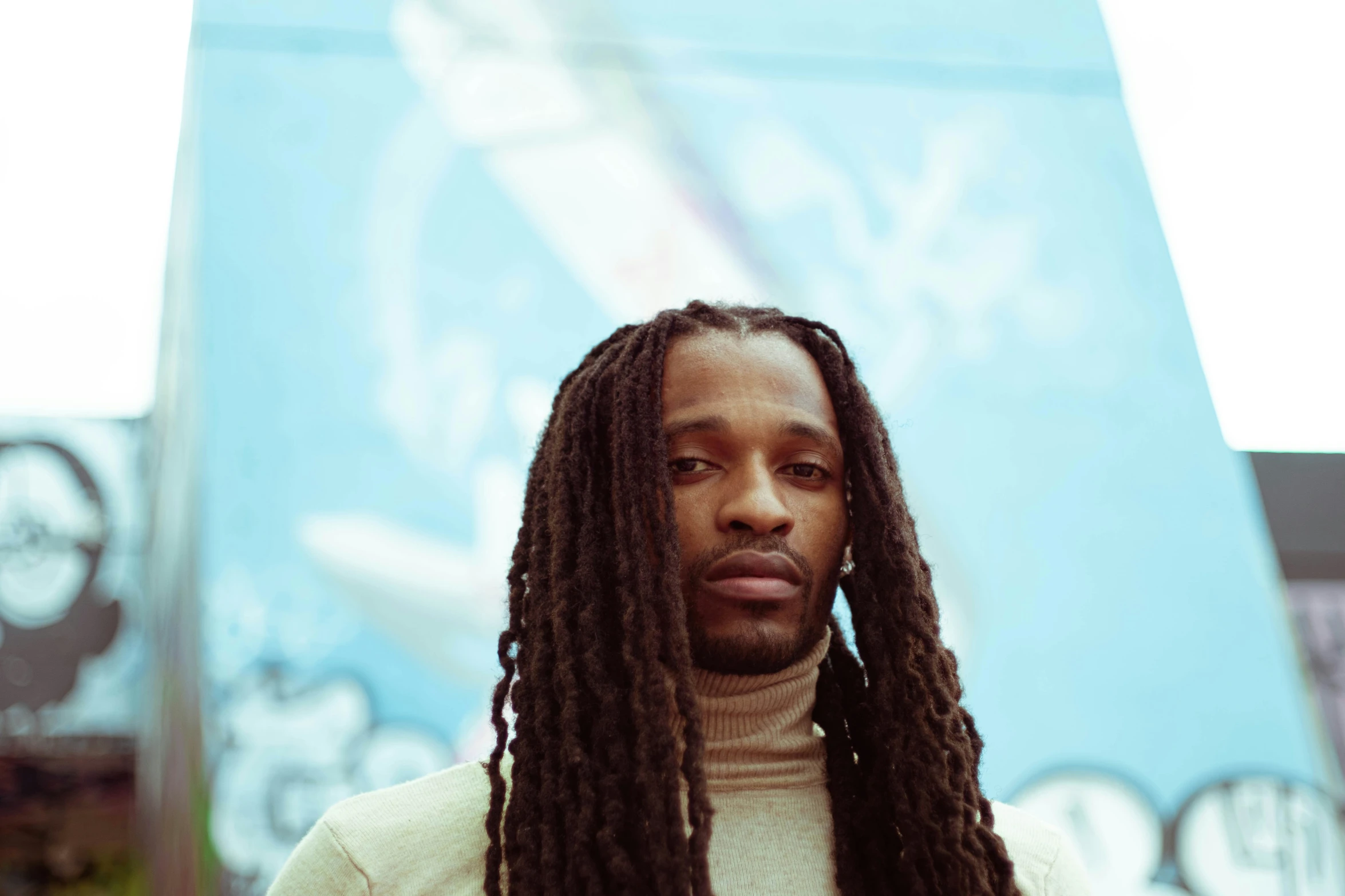 there is a man with long black dreadlocks standing in front of a banner