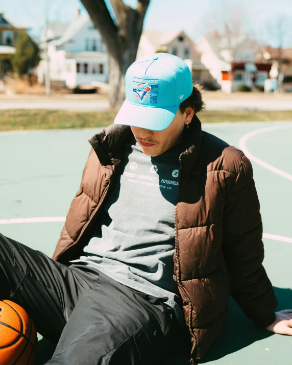 a man in a blue hat is sitting on a basketball court