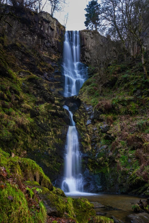 a water fall that is pouring over a lush green hillside