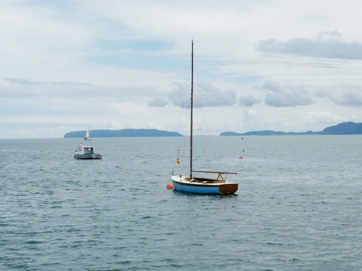 a sailboat out on the open ocean with a small boat nearby