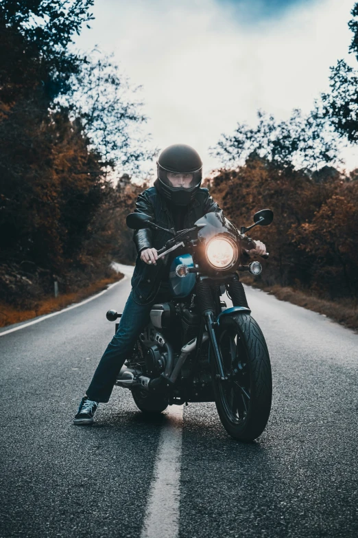 a man riding on the back of a motorcycle down a road