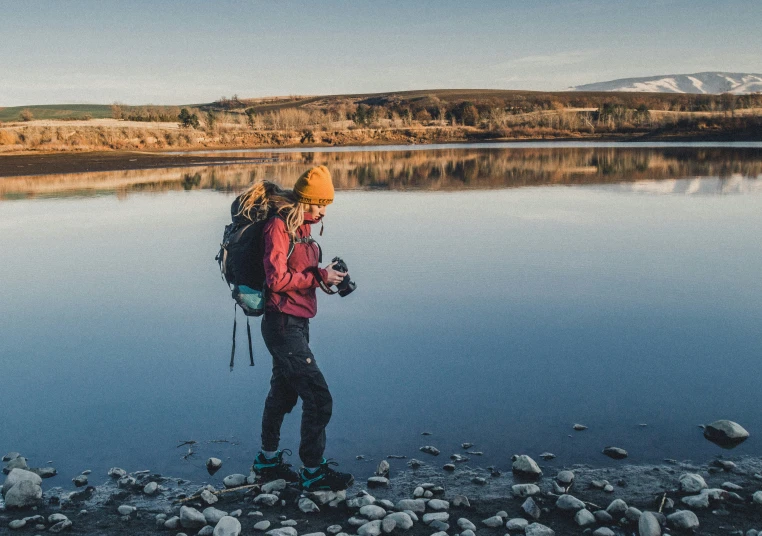 a man standing on rocks next to a lake in the daytime