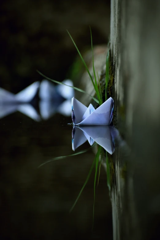 a white paper boat sits on water and is half submerged