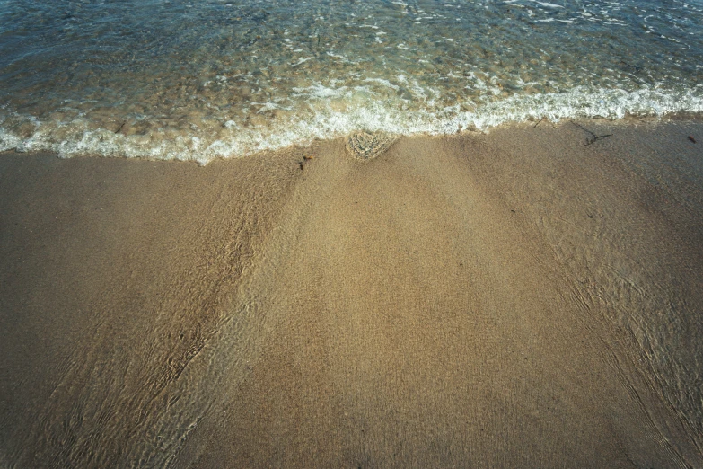 there are waves washing over the beach sand