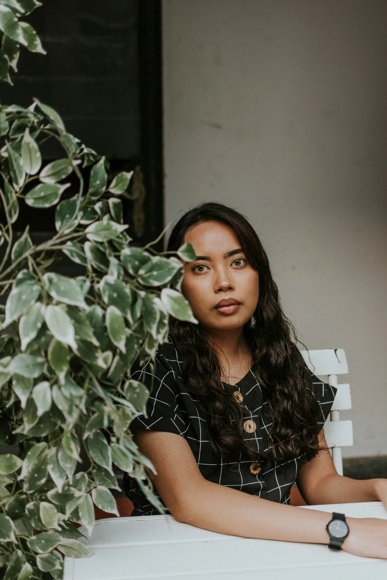 a young woman sitting at a table in front of a tree